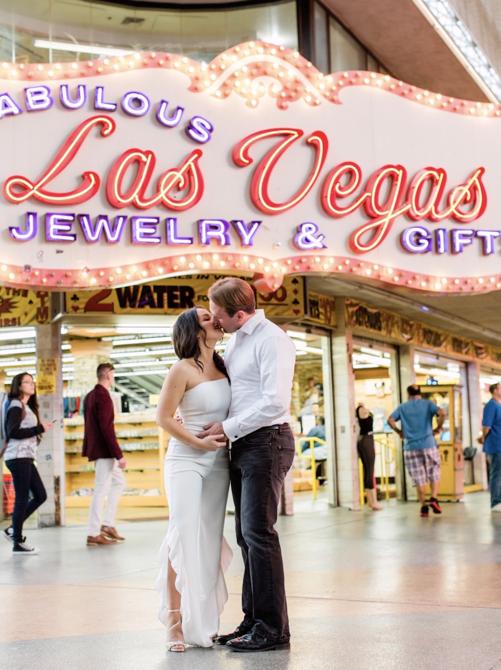 Bride and groom sharing a kiss in front of an establishment with a sign that reads Fabulous Las Vegas Jewelry & Gifts, taken by Elopement Las Vegas