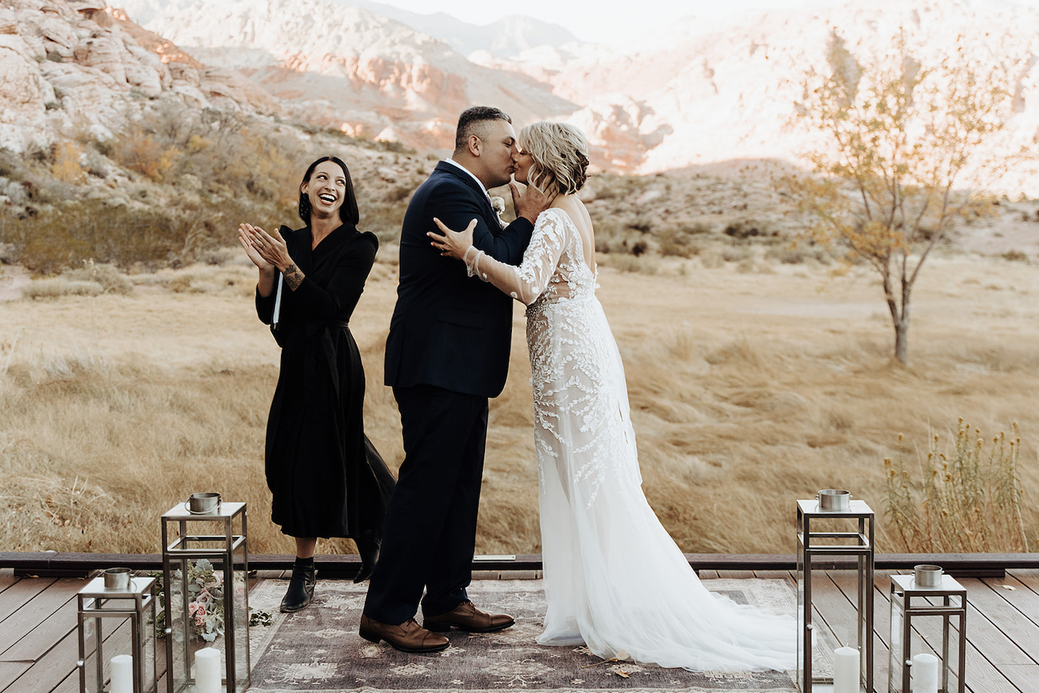 Couple sharing a kiss during their elopement ceremony in Las Vegas with their officiant clapping while walking away
