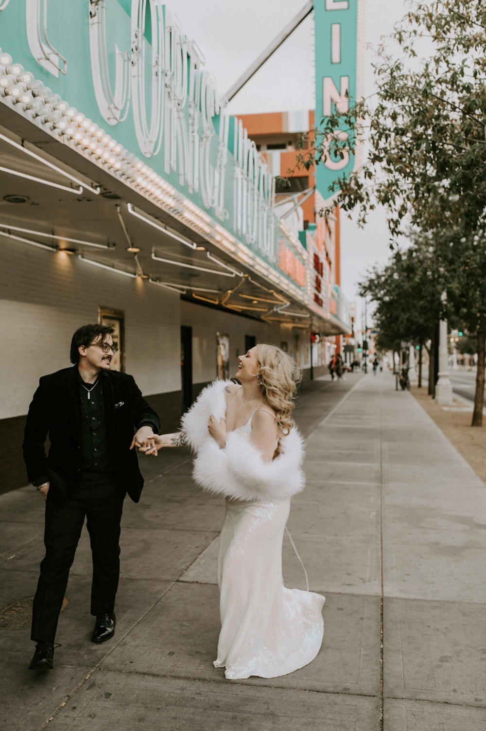 Bride and groom smiling at each other and holding hands as they casually walked around on The Strip, taken by Elopement Las Vegas