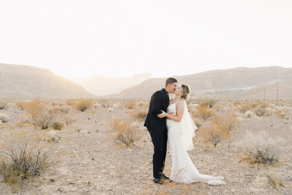 Couple wrapping their arms around each other and sharing kisses during their elopement shoot in Desert Love Land Off The Strip