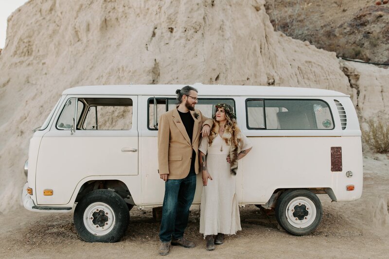 Bride and groom looking and smiling at each other as they pose in front of a vintage car at El Dorado Canyon Nelsons Ghost Town