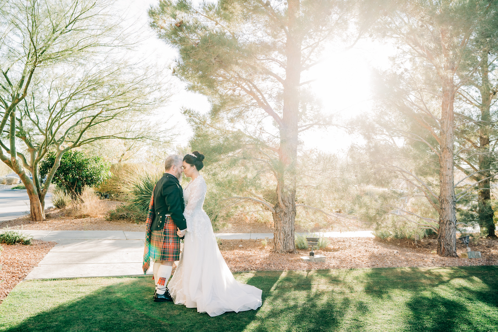 Couple (groom in kilt) on golf course with sun shining behind them at Paiute golf resort wedding shoot
