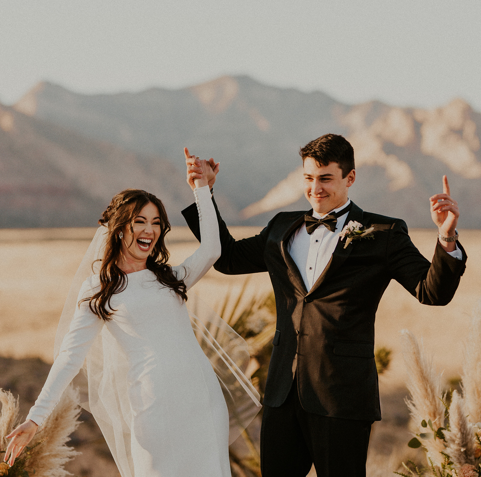 Bride and groom smile as they raise their hands during their elopement ceremony in Las Vegas