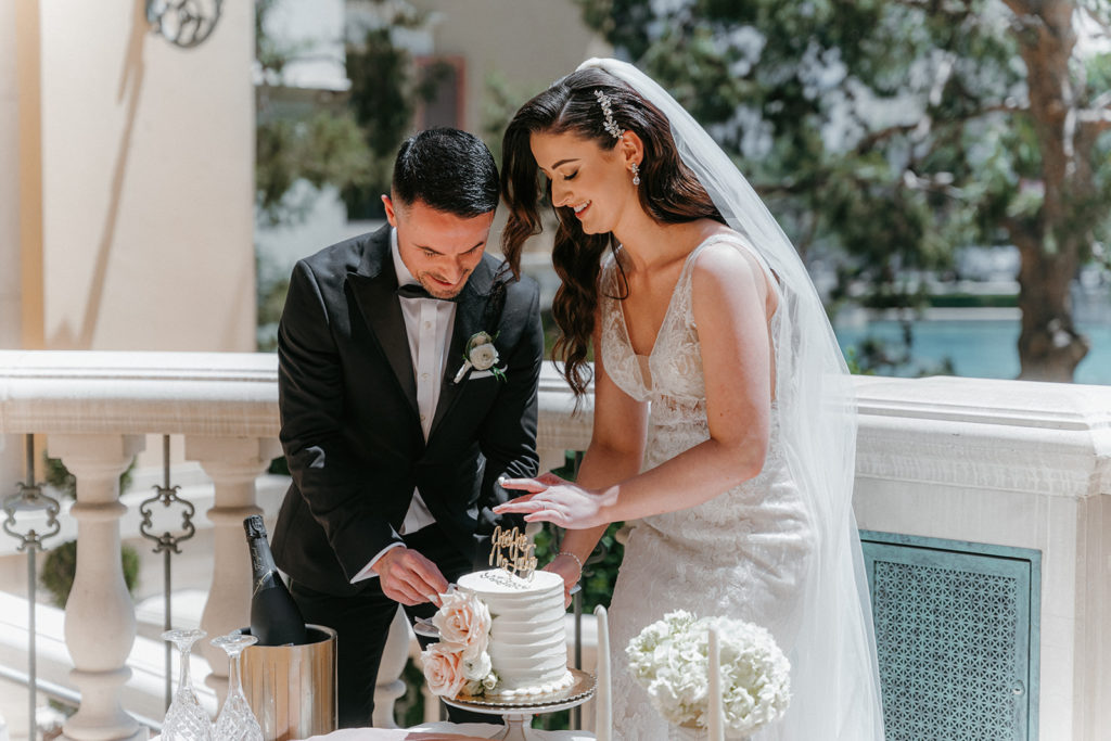 Bride and groom cutting a slice of their wedding cake together at their Las Vegas reception