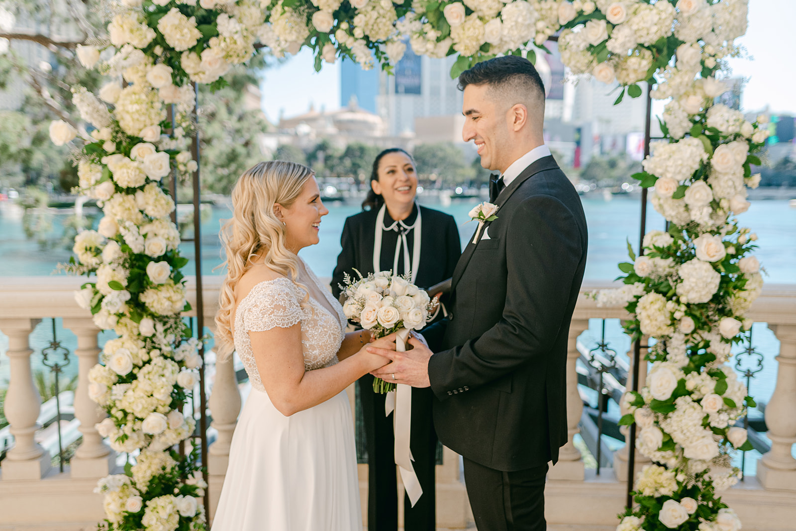 Bride and groom smiling at each other as they stand in front of an officiant during their wedding arranged by Elopement Las Vegas
