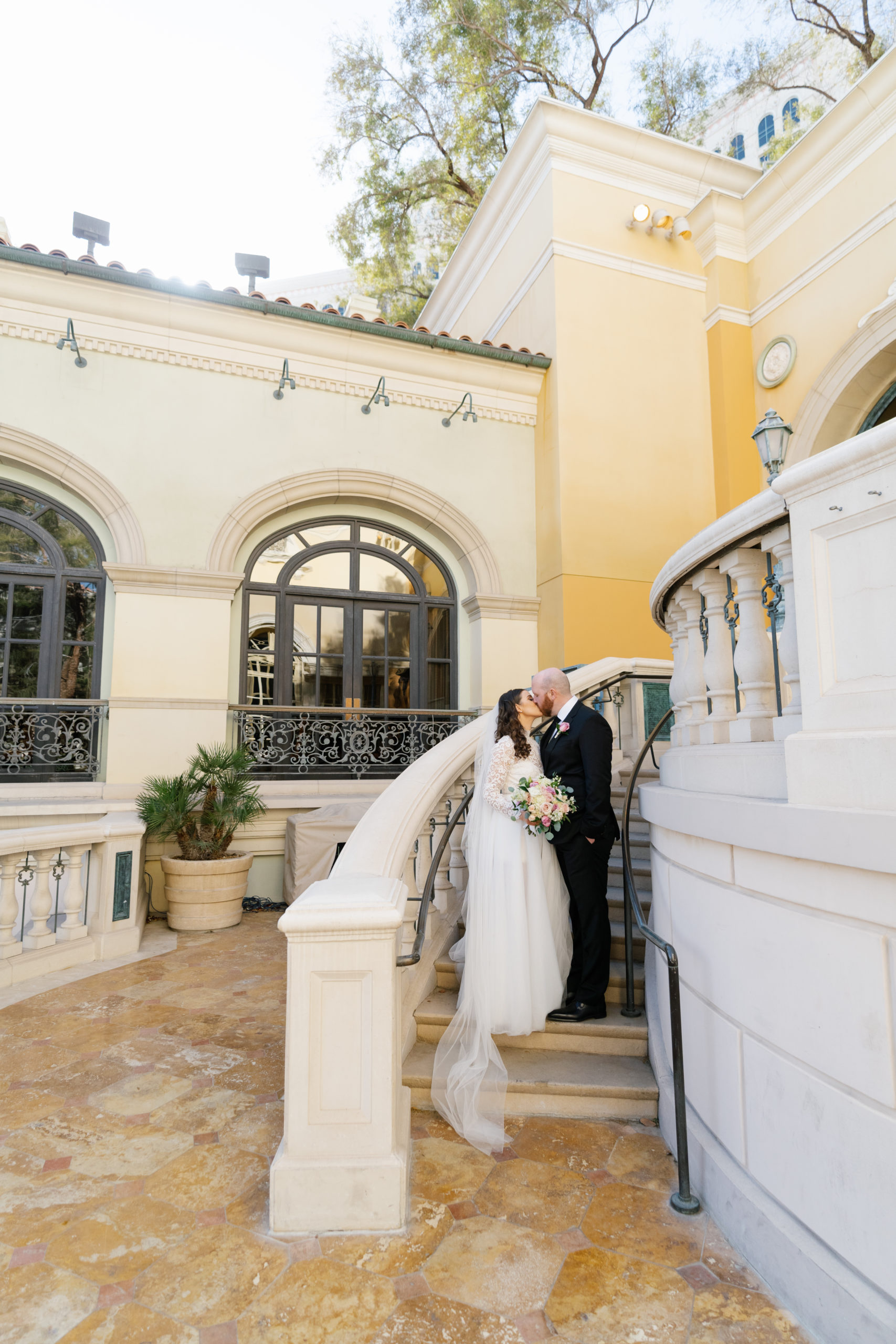 Bellagio Wedding Planning Guide: Bride and groom sharing a kiss at the staircase in their Las Vegas wedding venue