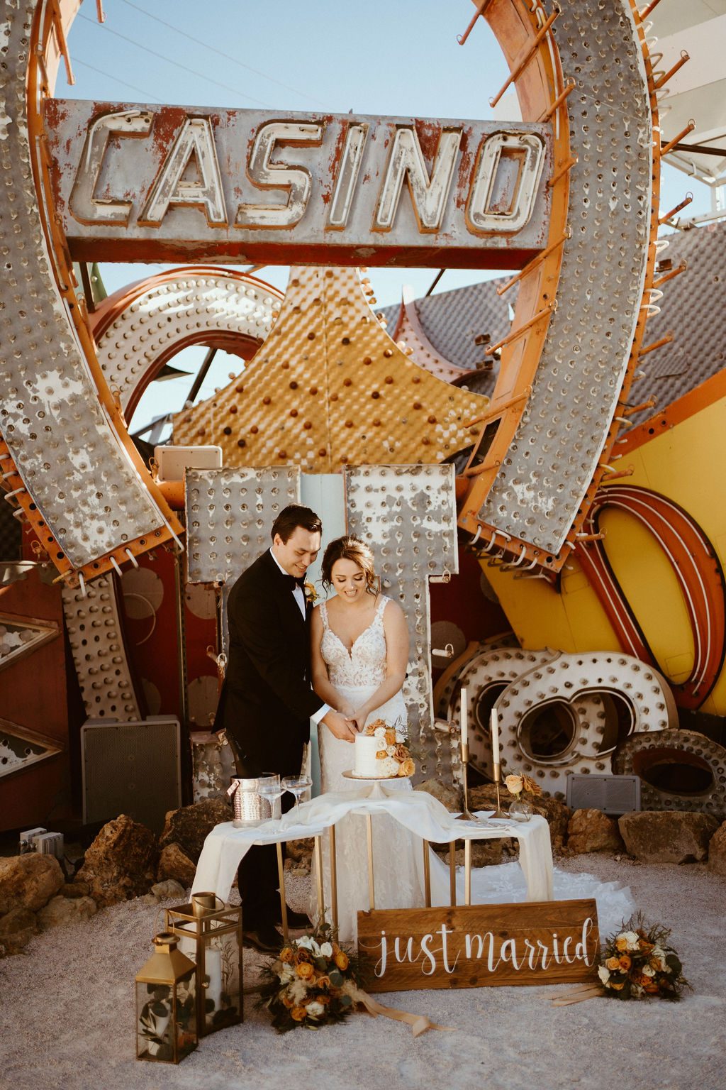 Couple cutting cake at the Neon Museum with wooden sign that reads Just Married