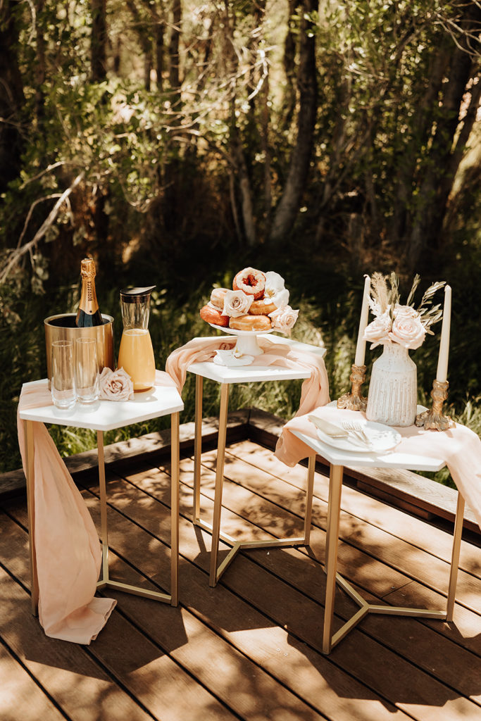 The Top All Inclusive Elopement Packages. Donuts laid on tray placed on table with champagne and flowers and candles beside it for the elopement.
