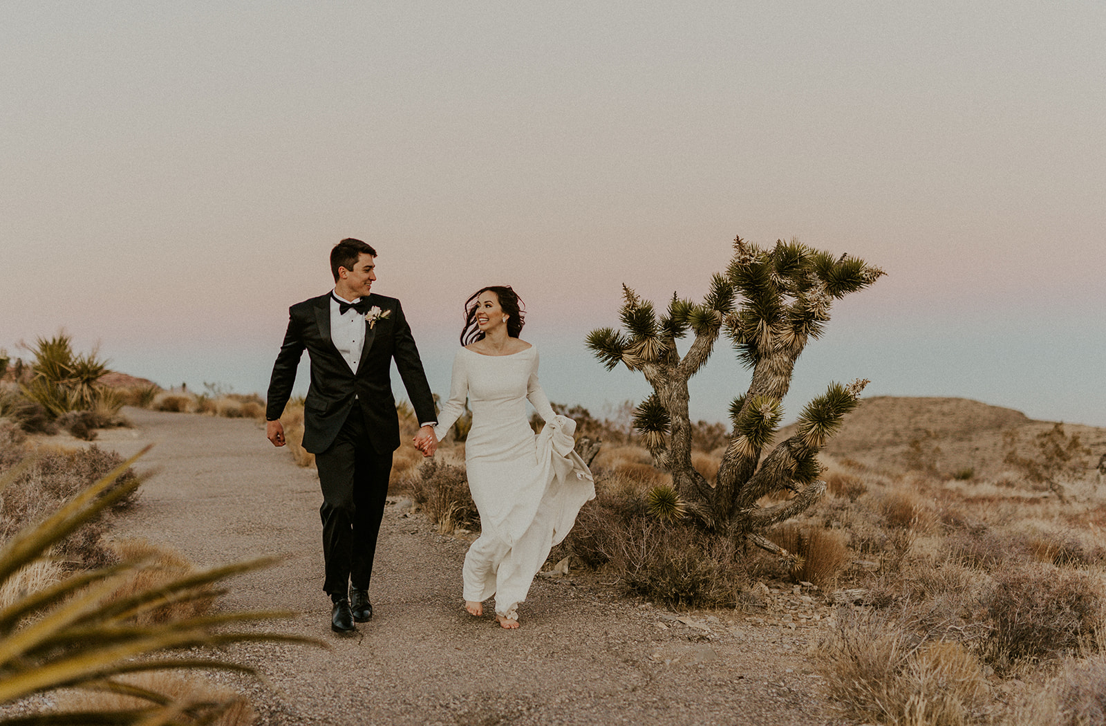 Couple smiling at each other as they hold hands while walking during their Las Vegas wedding shoot