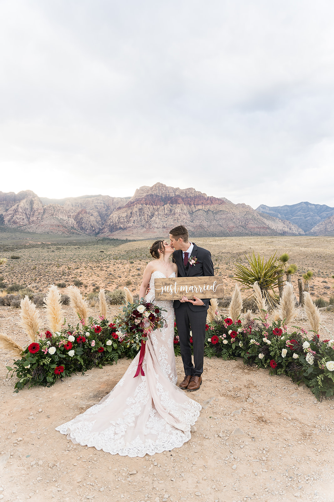 Bride and groom sharing a kiss as they hold up Just Married sign at Red Rock Canyon Off the Strip in Las Vegas