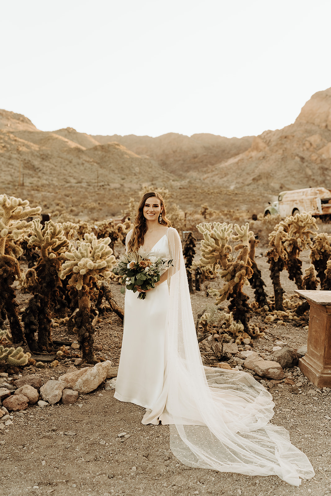 Stunning bride smiles while holding her bouquet at the Cholla Cactus Fields