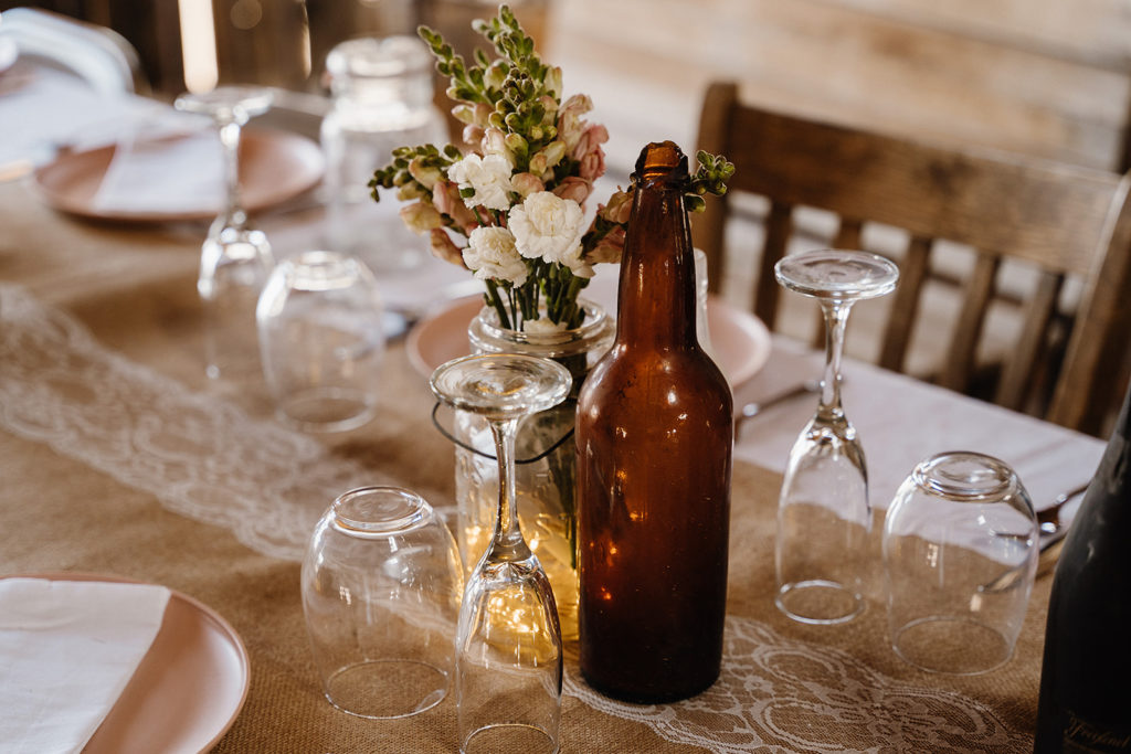 Close-up shot of Nelson Ghost Town wedding reception table with glasses and a floral centerpiece