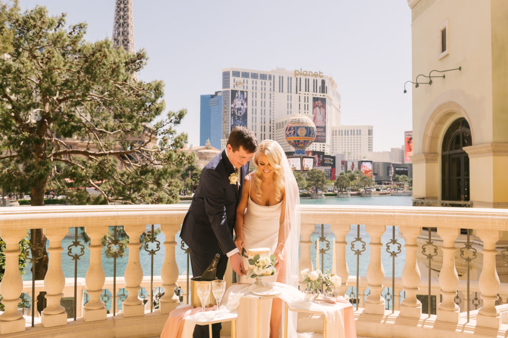 Couple smiling as they cut a slice of their cake at the Bellagio, one of the best venues to get married in Vegas