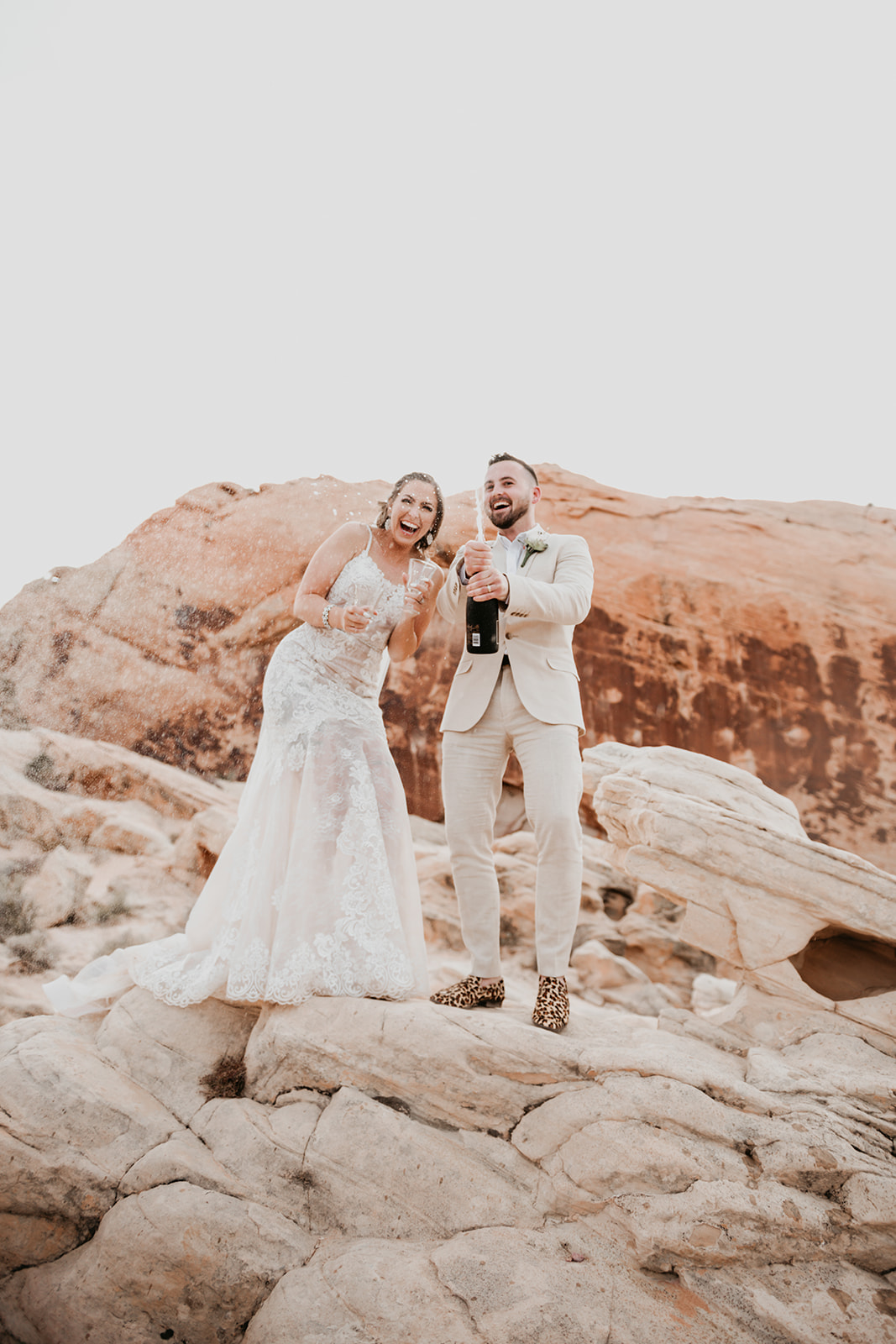 Couple candidly smiling as they pop open a bottle of champagne during elopement coordinated by Elopement Las Vegas