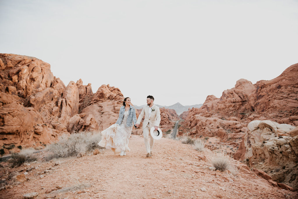 Couple holding hands and walking together in the Valley of Fire during elopement planned by Elopement Las Vegas