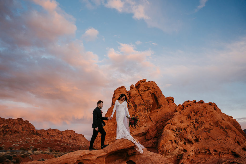 Couple holding hands as they pose at the rocks in the Valley of Fire for their elopement shoot