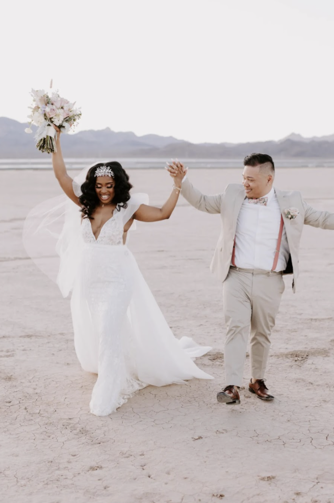 Newlywed couple holding hands and raising them during their Dry Lake Bed elopement shoot