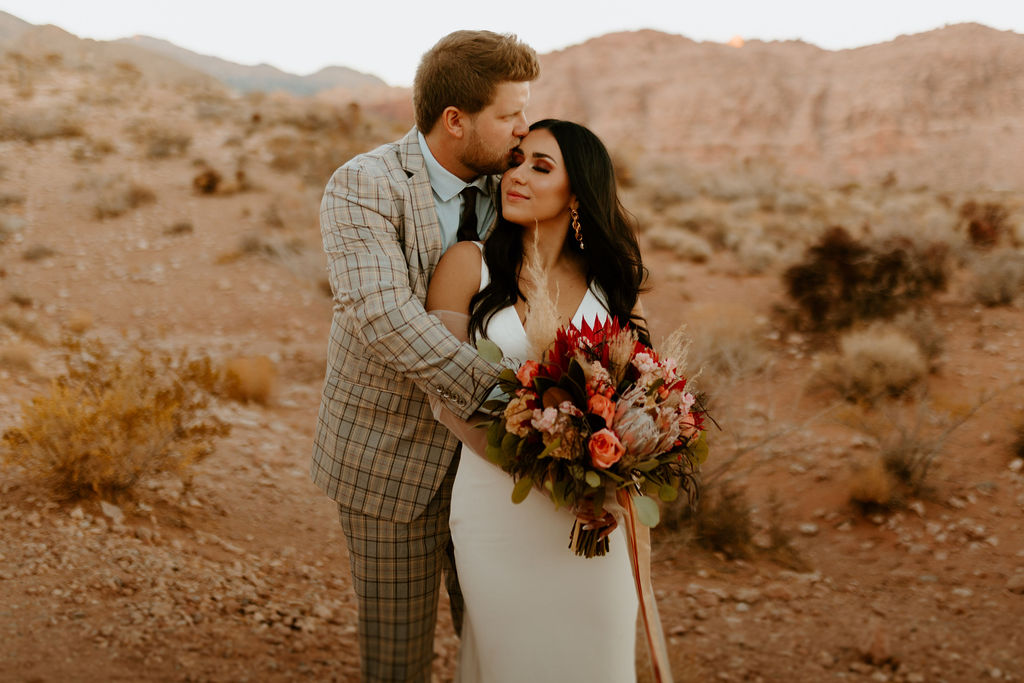 Groom hugging bride from behind during their Red Rock Canyon elopement shoot
