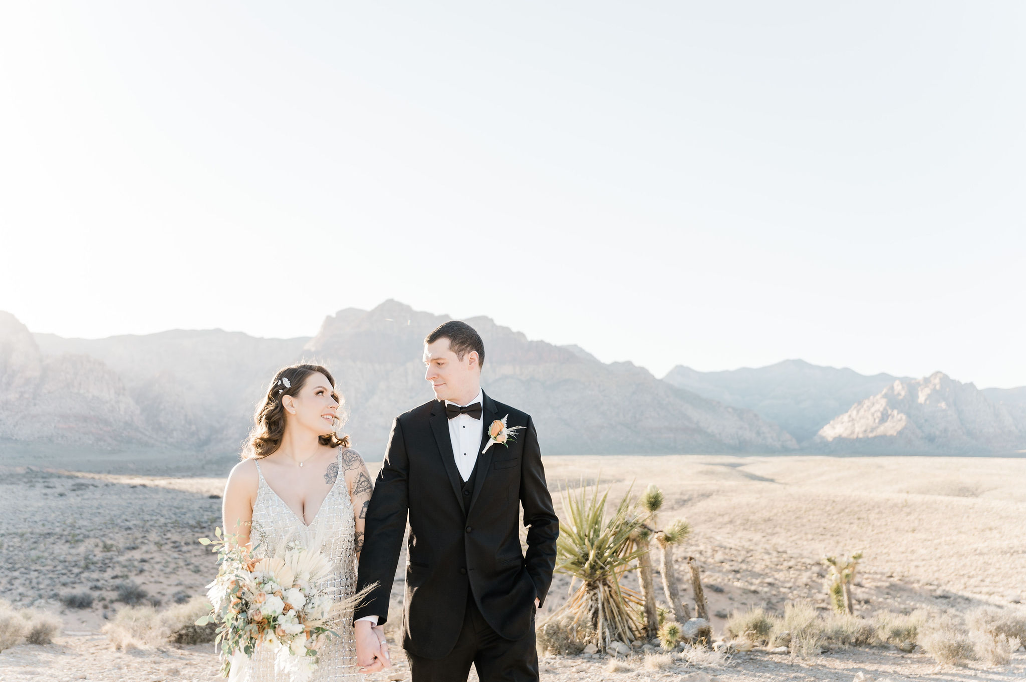 Bride and groom holding hands and looking at each other endearingly during their elopement shoot organized by Elopement Las Vegas