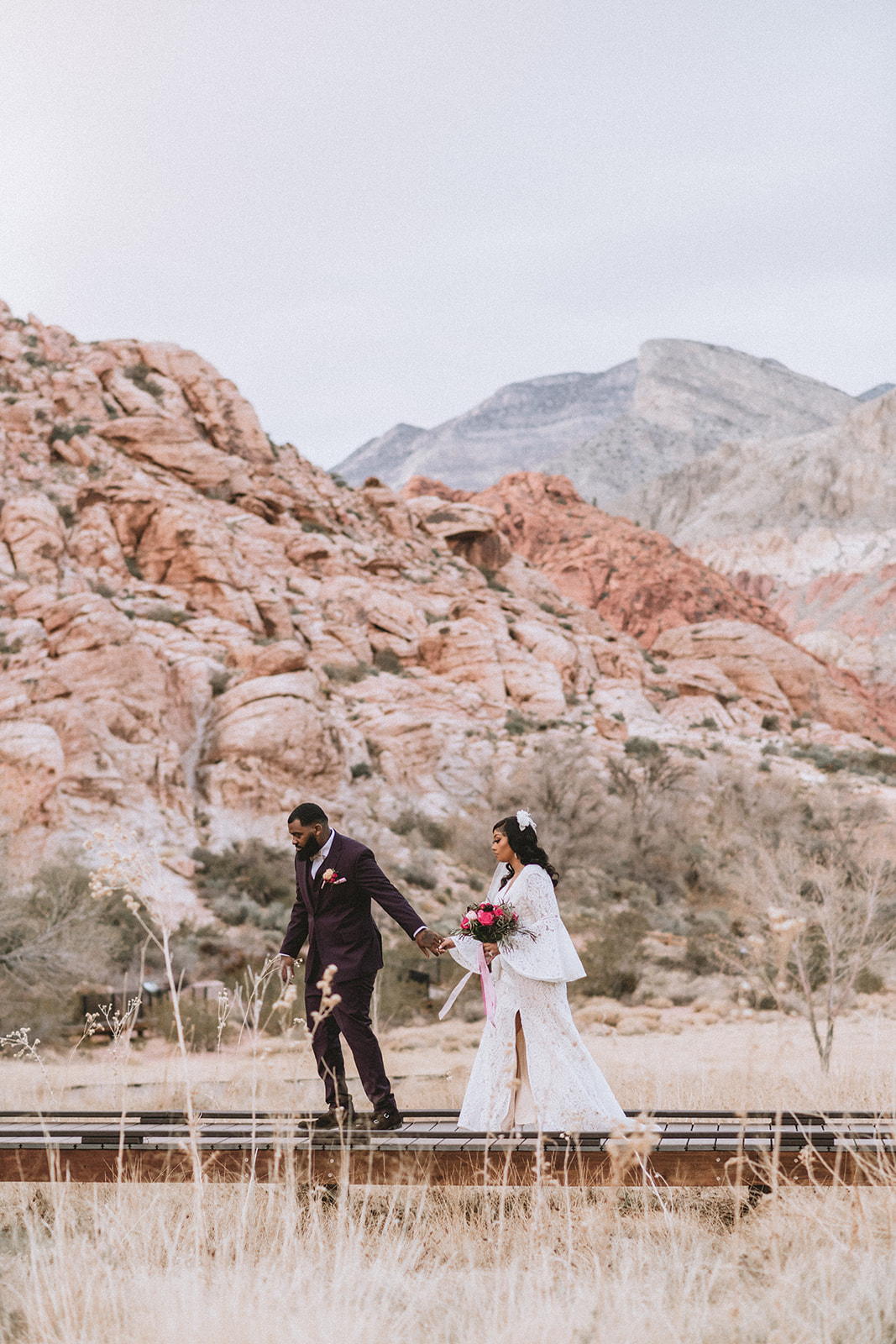 Bride and groom holding hands as they walk along the path during their elopement shoot organized by Elopement Las Vegas