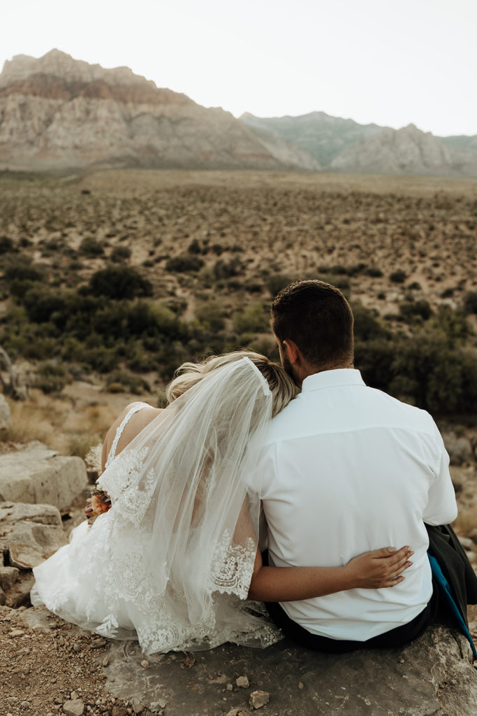 How To Plan The Perfect Red Rock Canyon Elopement (Las Vegas). Bride and groom sitting together with their backs to the camera.