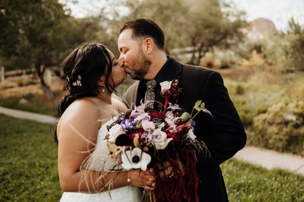 Couple kissing with bouquet and boutonniere in the photo during elopement shoot arranged by Elopement Las Vegas