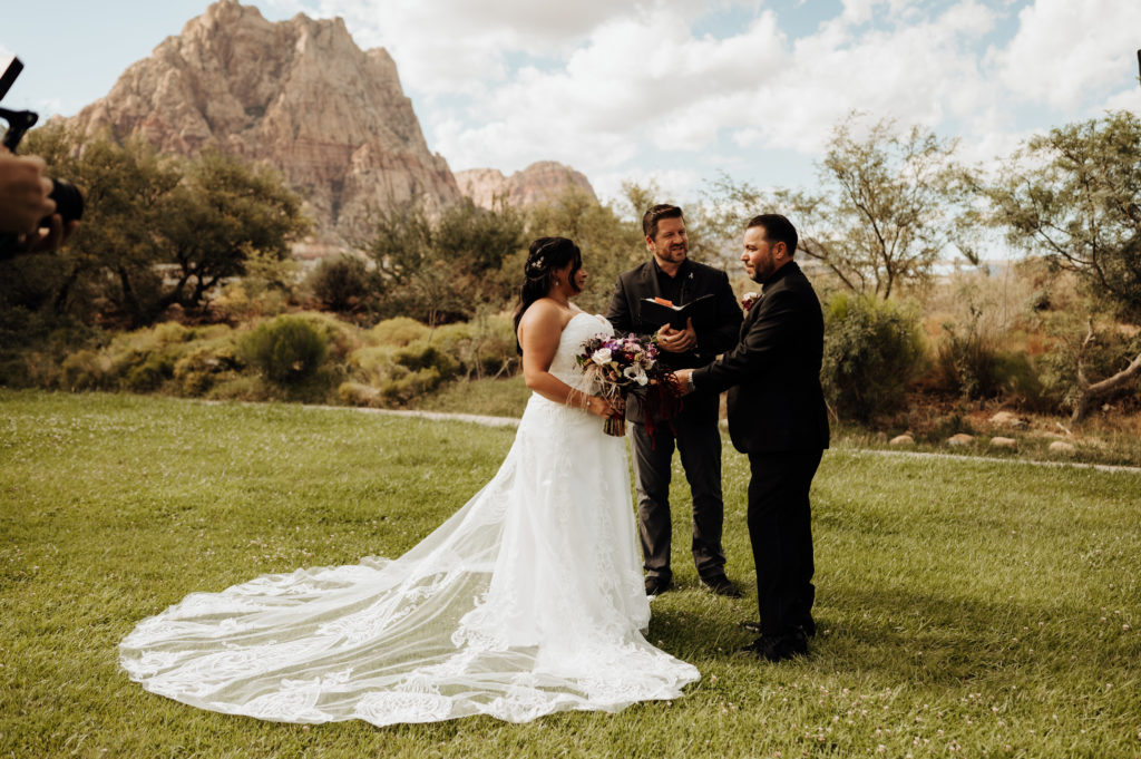 Bride and groom holding hands in front of the officiant at ceremony in Spring Mountain Ranch