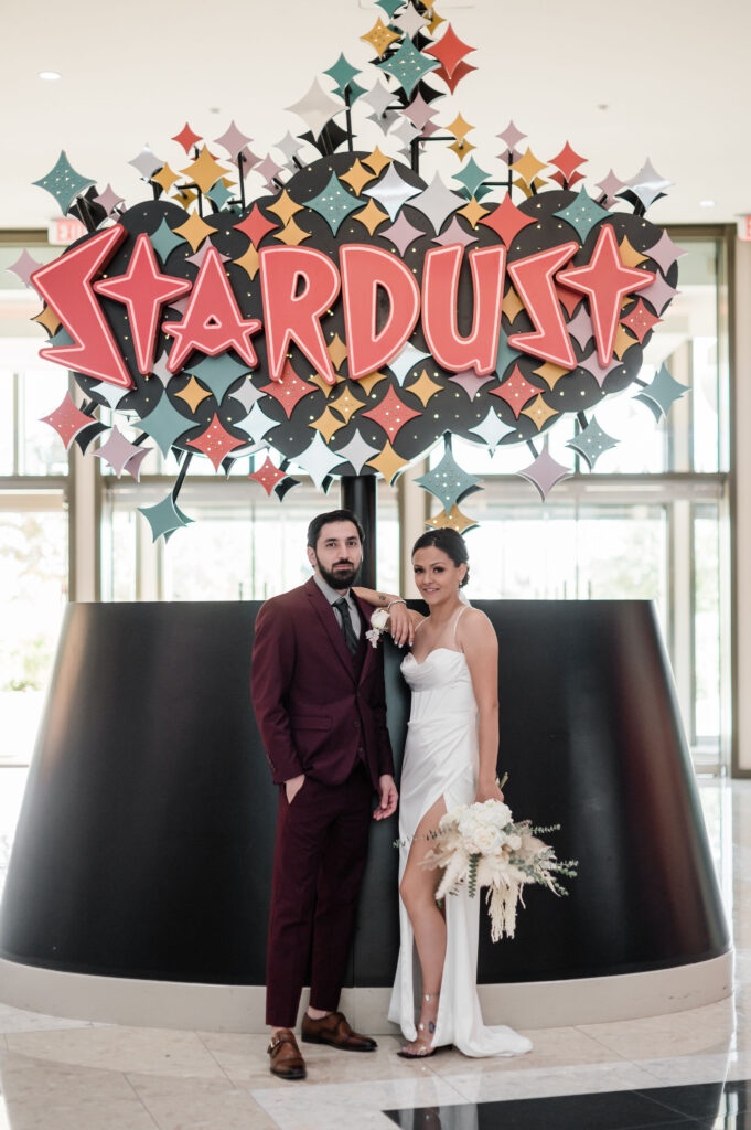Resorts World Hotel and Casino Wedding and Elopement Guide. Couple standing next to each other in front of Stardust sign.