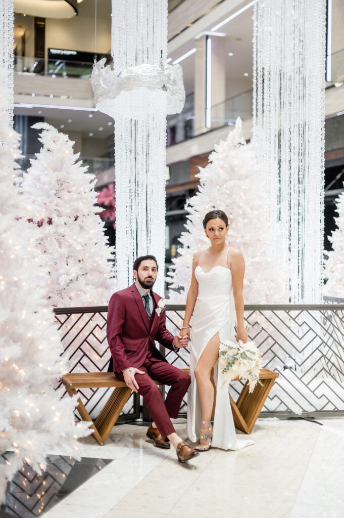 Bride and groom holding hands in front of white Christmas decorations during Las Vegas elopement shoot