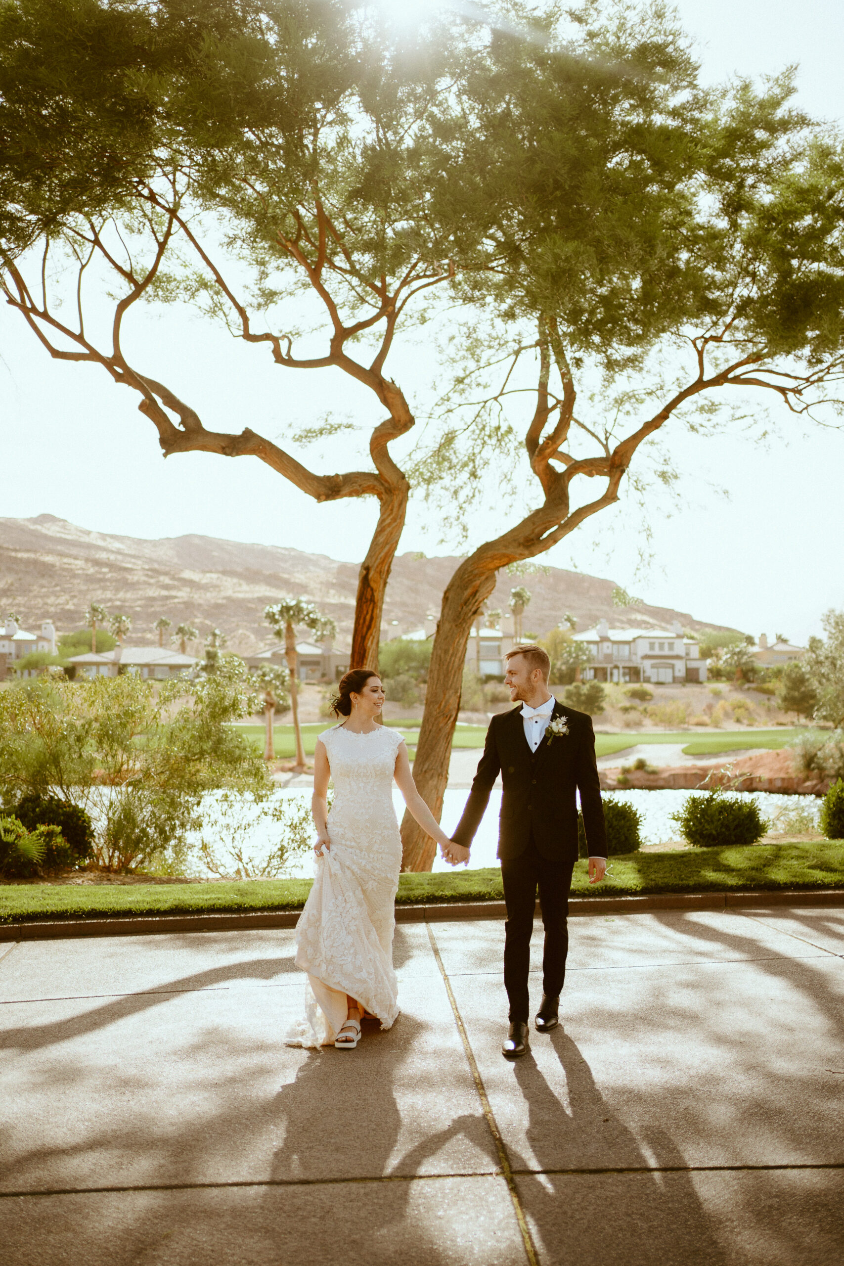 Newlywed couple holding hands and smiling at each other during their Red Rock Country Club wedding shoot