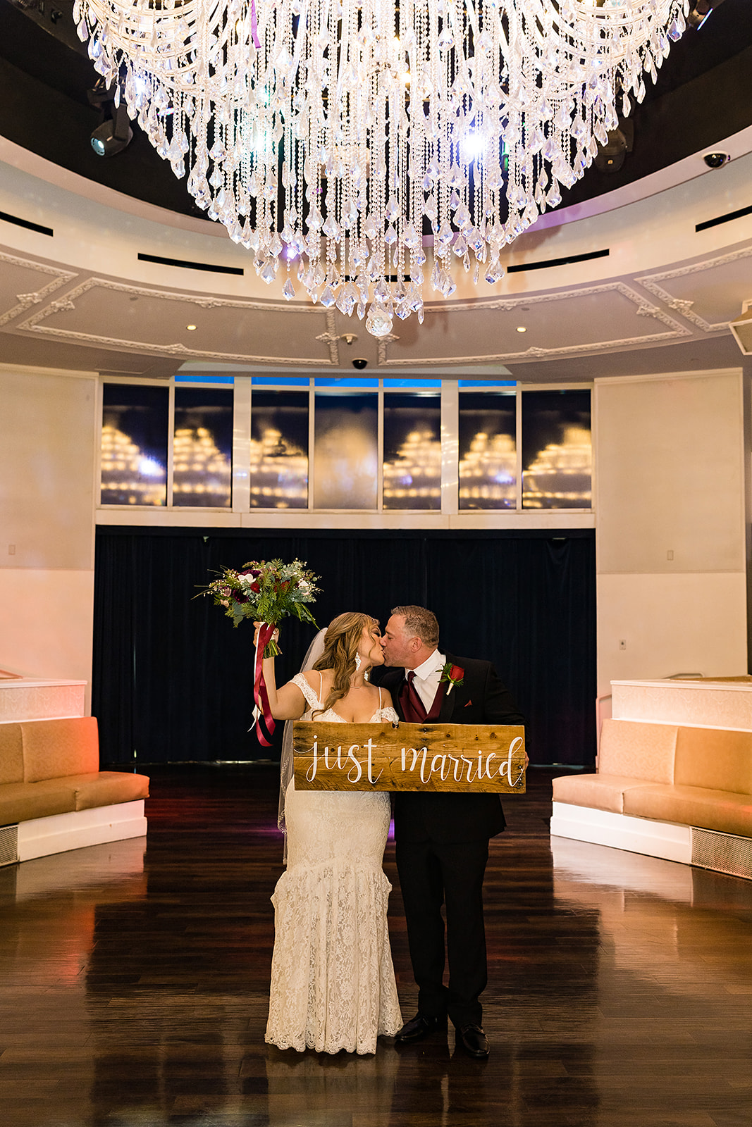 Couple sharing a kiss during their elopement shoot in Las Vegas while holding up Just Married sign