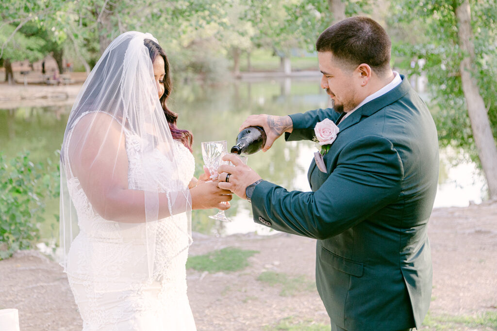 Groom pouring champagne into bride's glass during their Tule Springs Wedding Shoot