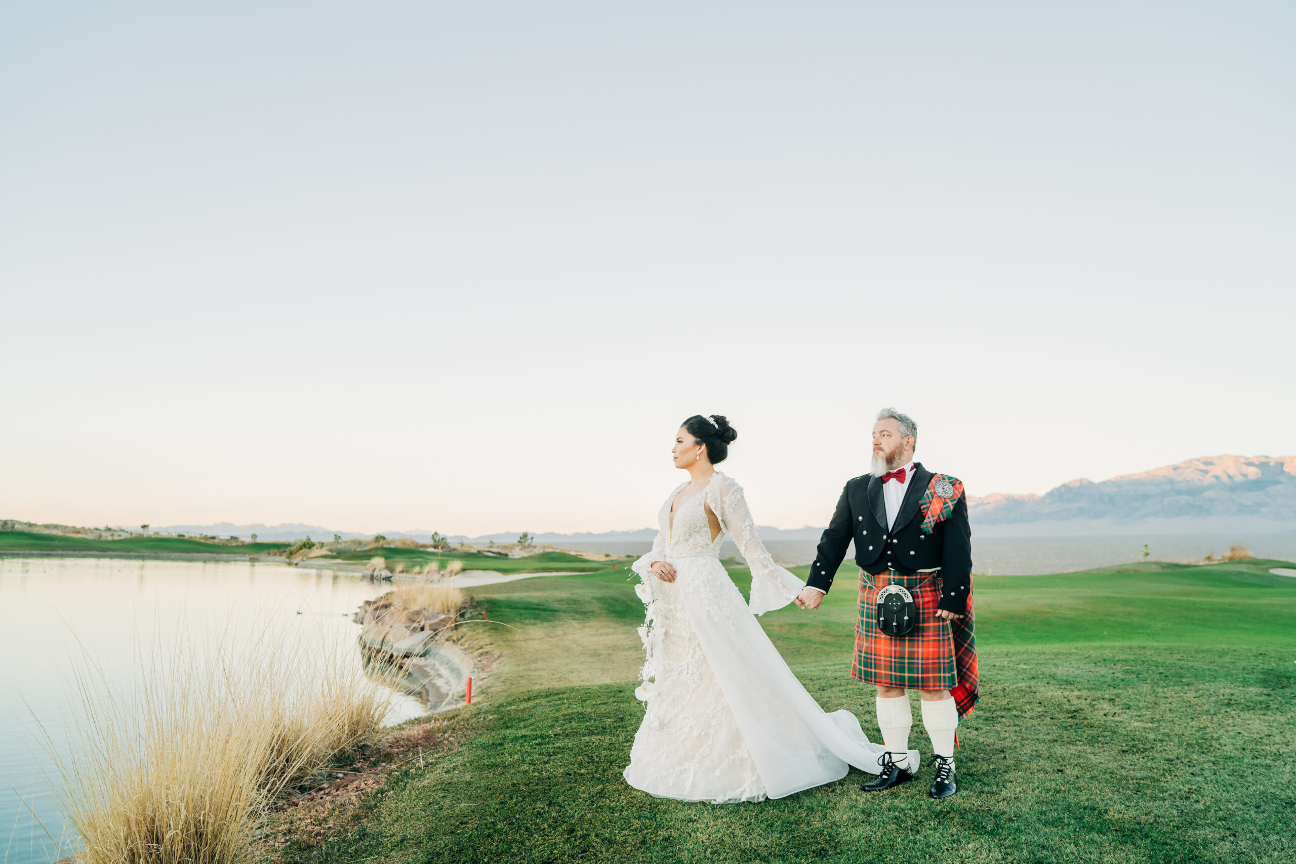 Bride and groom holding hands while looking off into the distance at Paiute Golf Course