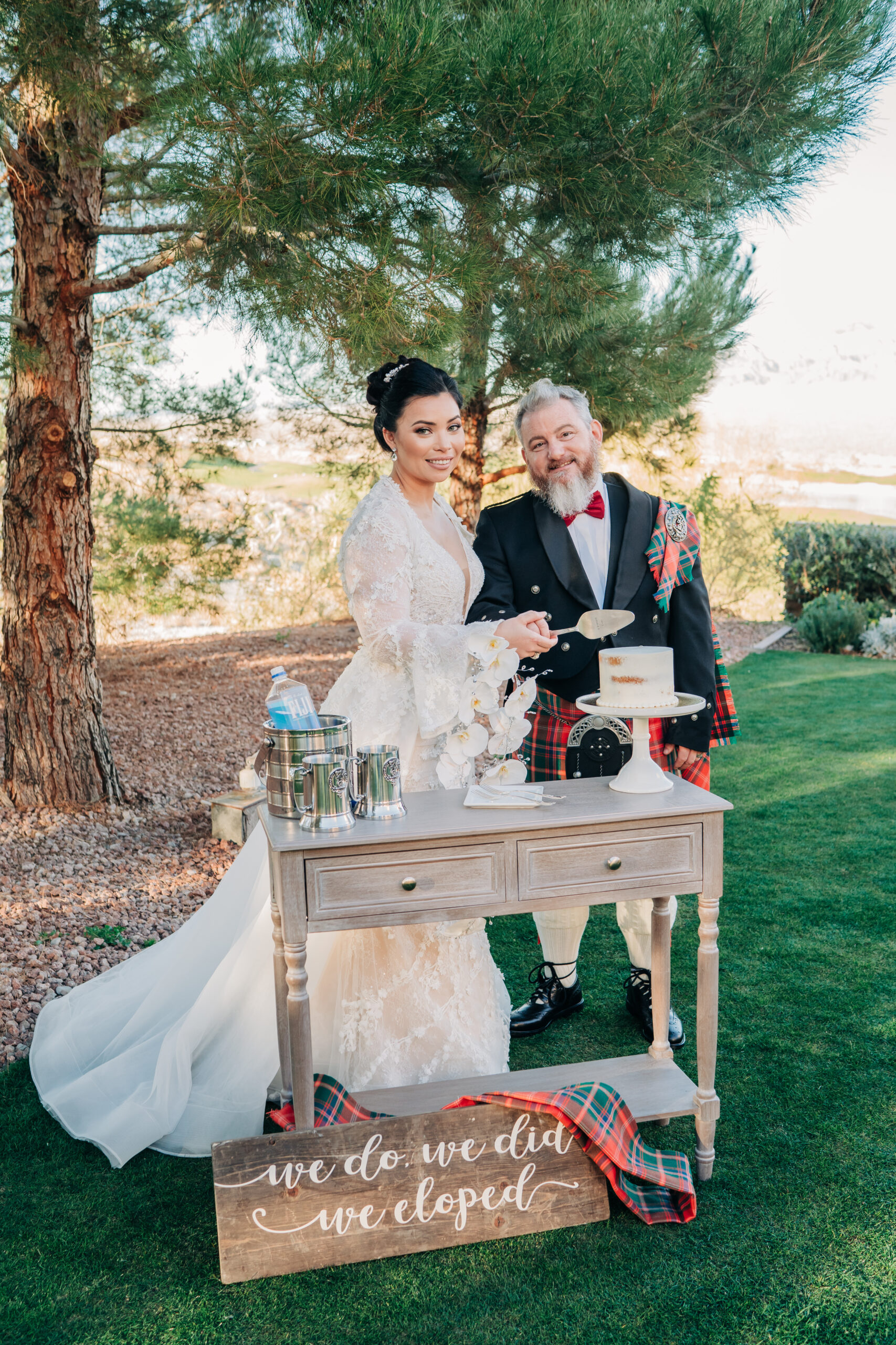 Newlywed couple smiling at the camera as they are about to slice their wedding cake at Paiute Golf Course