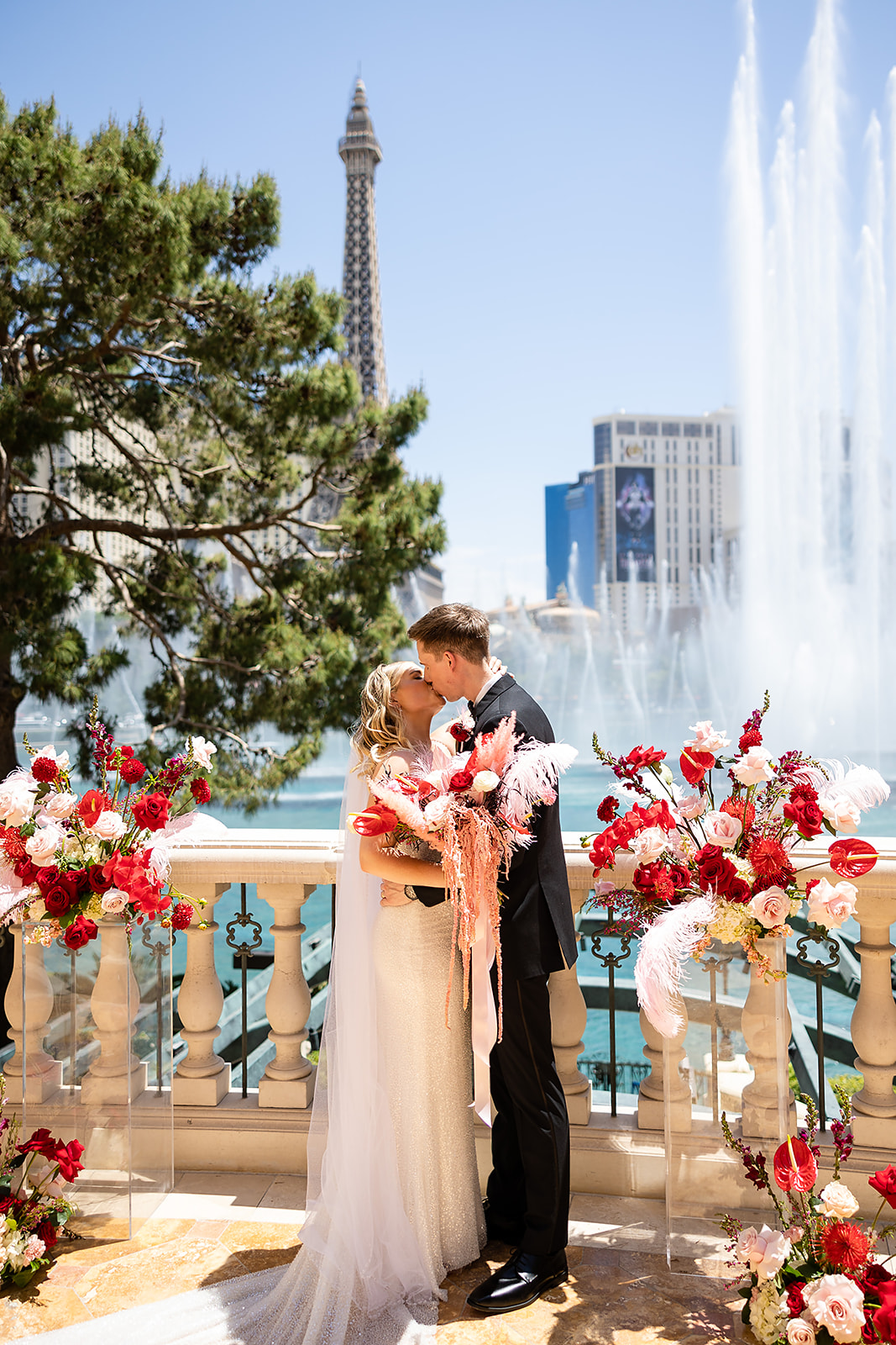 Newlywed couple sharing a kiss in front of fountain during their wedding shoot organized by Elopement Las Vegas