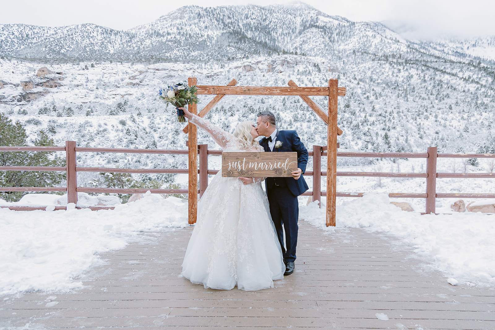 Bride and groom sharing a kiss as they hold up Just Married sign during Mount Charleston wedding shoot