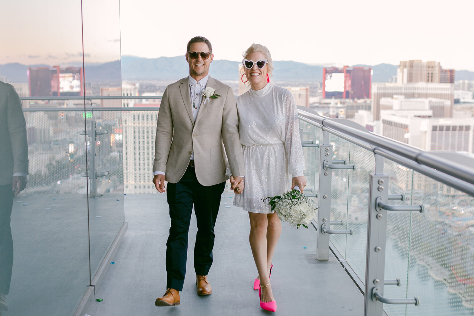 Bride and groom wearing sunglasses as they hold hands during their elopement shoot arranged by Elopement Las Vegas