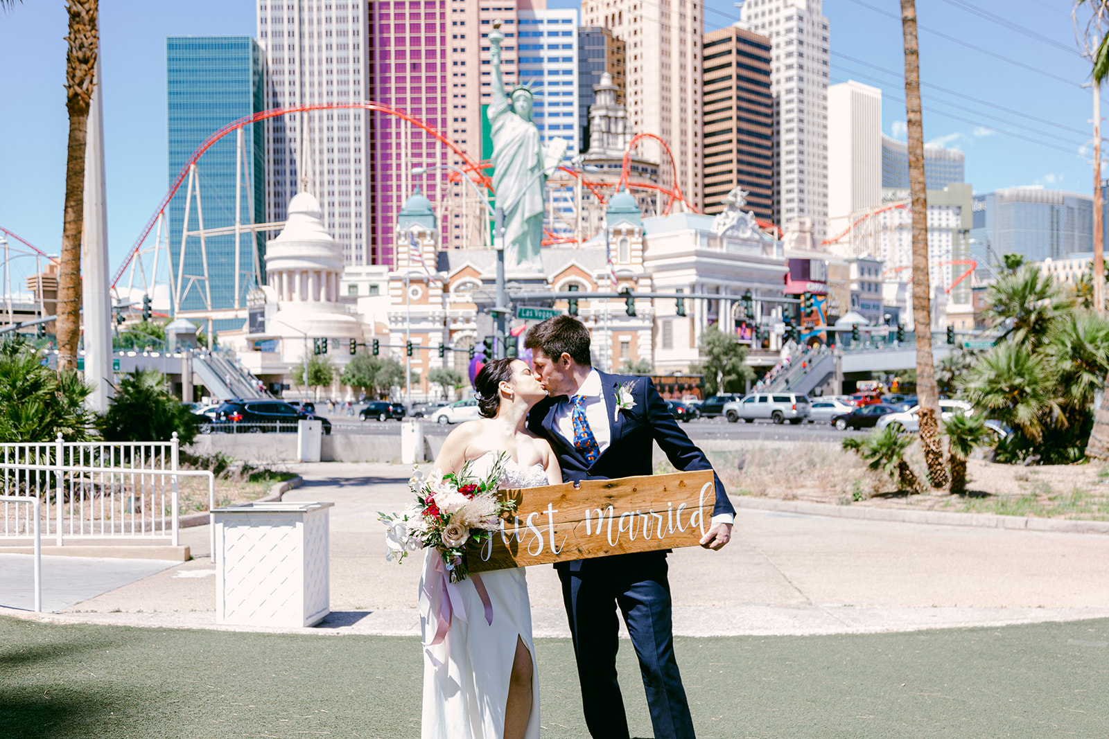 Bride and groom sharing a kiss as they hold up Just Married sign during their elopement arranged by Elopement Las Vegas